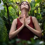 Femme méditant en pleine forêt lors d’une pratique holistique de bien-être et de reconnexion à la nature