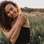 Femme dans un champs de blé qui s'enlace pour rechercher la sécurité émotionnelle.